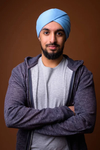 Young bearded Indian Sikh man wearing turban against brown backg — 스톡 사진