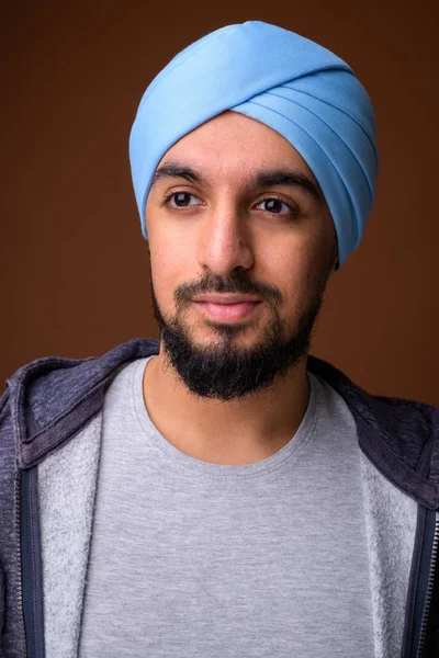 Joven barbudo hombre Sikh indio usando turbante contra respaldo marrón — Foto de Stock