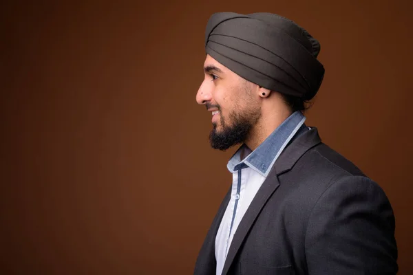 Giovane barbuto indiano Sikh uomo d'affari indossa turbante contro bro — Foto Stock