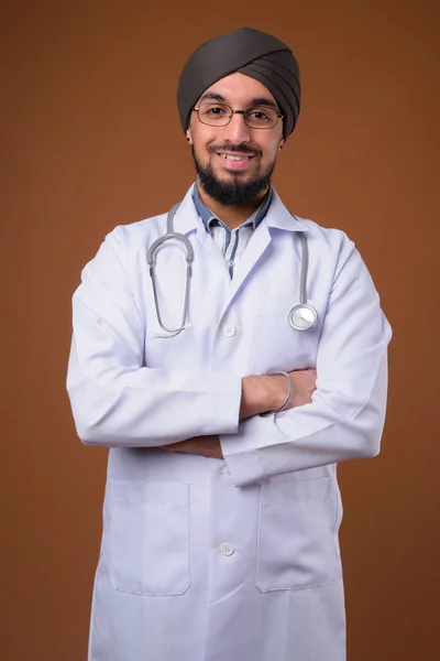 Mladý vousatý indický sikh muž lékař nosí turban proti čelu — Stock fotografie