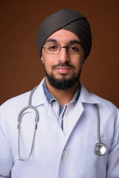 Młody brodaty indyjski Sikh człowiek lekarz noszenie turban przeciw brwi — Zdjęcie stockowe