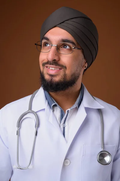 Young bearded Indian Sikh man doctor wearing turban against brow — 스톡 사진