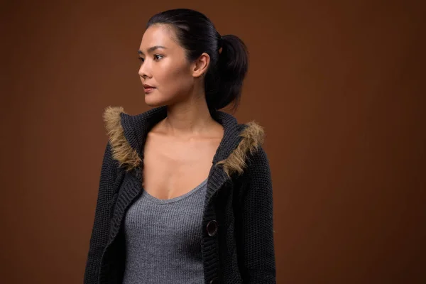 Studio skott av vacker asiatisk kvinna mot brun bakgrund — Stockfoto