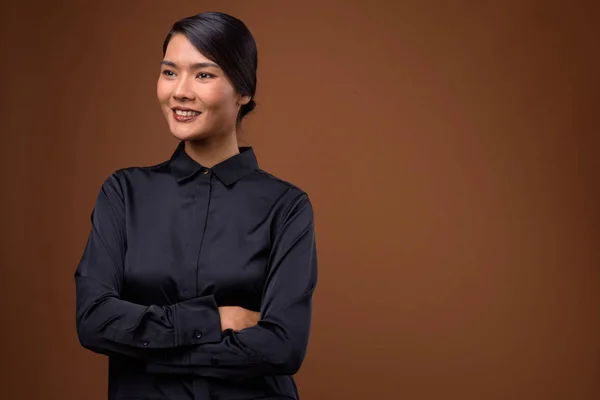 Studio shot van mooie Aziatische zakenvrouw tegen bruine ACHTERG — Stockfoto