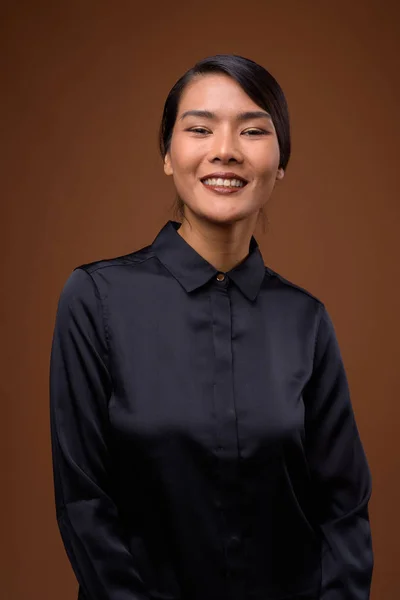 Estudio disparo de hermosa mujer de negocios asiática contra respaldo marrón —  Fotos de Stock