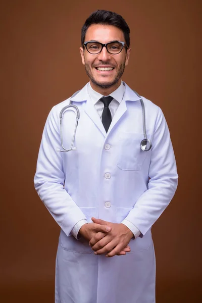 Jeune bel homme hispanique médecin sur fond brun — Photo