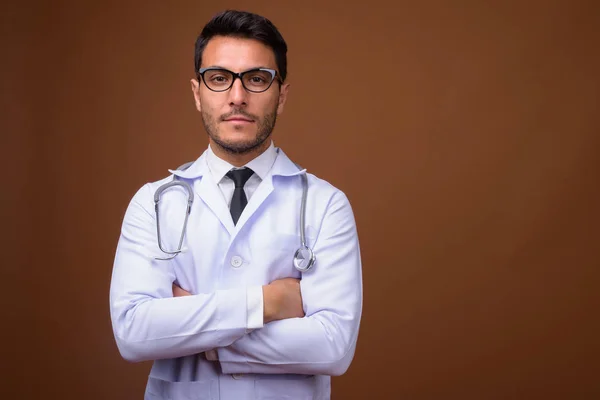 Jovem bonito homem hispânico médico contra fundo marrom — Fotografia de Stock