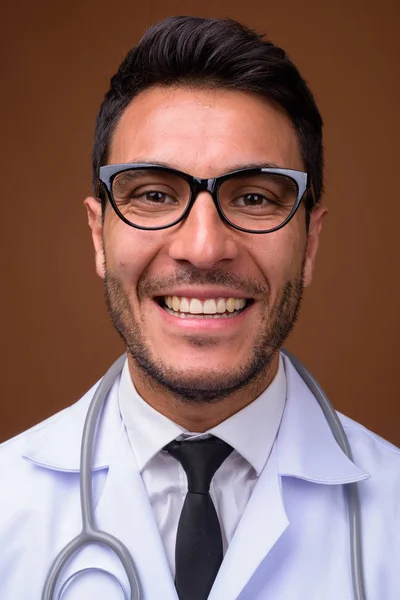 Mladý pohledný hispánec muž lékař proti hnědé pozadí — Stock fotografie