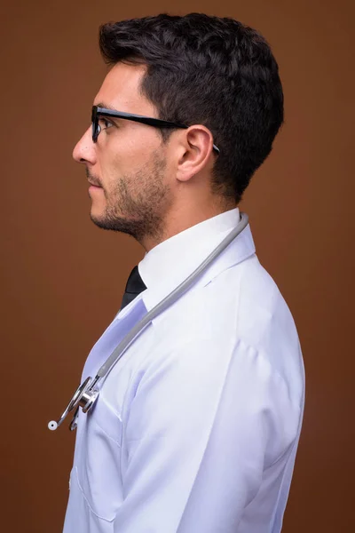 Young handsome Hispanic man doctor against brown background — Stock Photo, Image