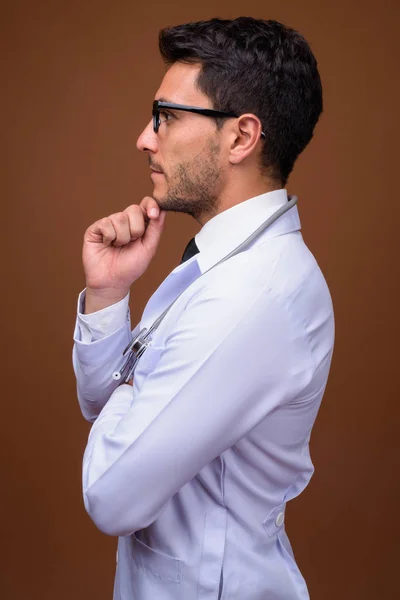 Jovem bonito homem hispânico médico contra fundo marrom — Fotografia de Stock