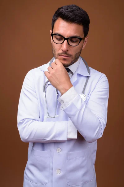 Joven guapo hispano hombre doctor contra marrón fondo — Foto de Stock