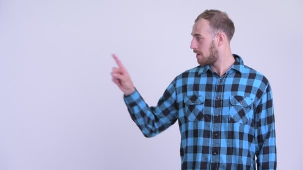 Gelukkig bebaarde hipster man aanraken van iets en op zoek verrast — Stockvideo