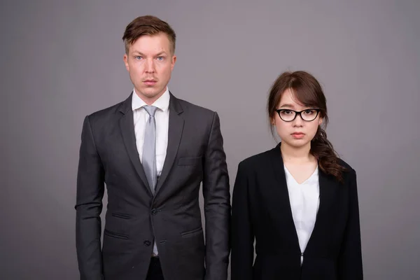 Jeune homme d'affaires et jeune femme d'affaires asiatique contre le bac gris — Photo