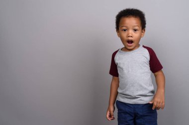 Studio shot of young cute African boy against gray background