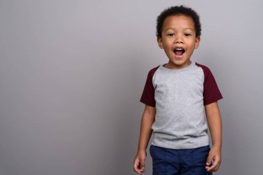 Studio shot of young cute African boy against gray background
