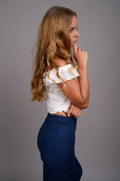 Jovem mulher bonita com cabelo loiro contra fundo cinza — Fotografia de Stock
