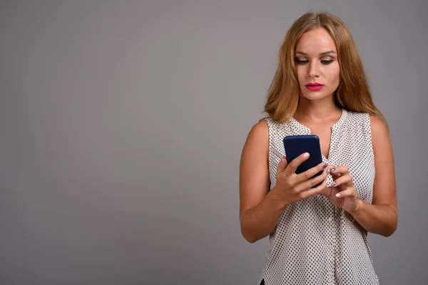 Young beautiful businesswoman with blond hair against gray backg — Stock Photo, Image