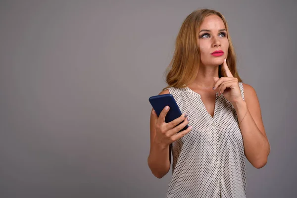 Young beautiful businesswoman with blond hair against gray backg — Stock Photo, Image