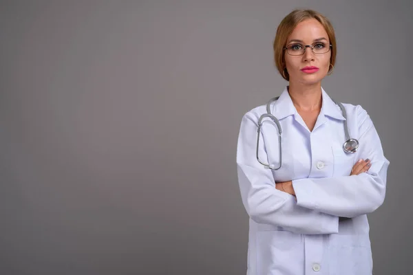 Jovem médico mulher bonita com cabelo loiro contra backgr cinza — Fotografia de Stock