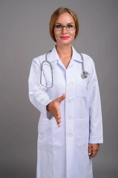 Jovem médico mulher bonita com cabelo loiro contra backgr cinza — Fotografia de Stock