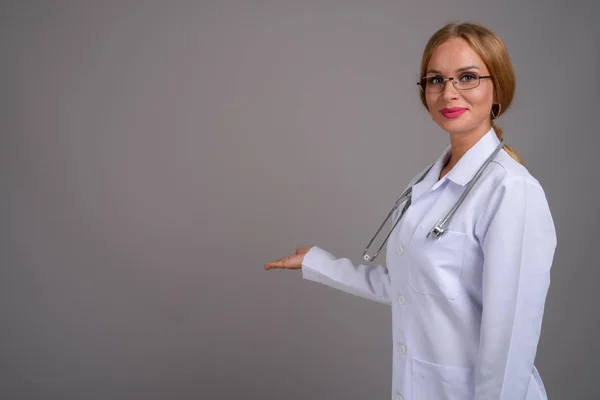 Giovane bella donna medico con i capelli biondi contro backgr grigio — Foto Stock