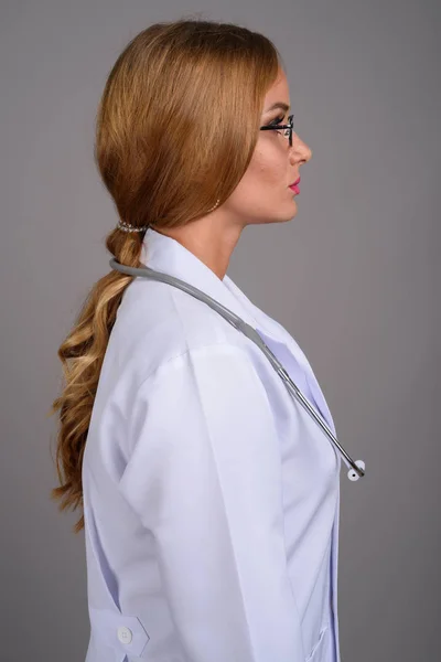 Jovem médico mulher bonita com cabelo loiro contra backgr cinza — Fotografia de Stock