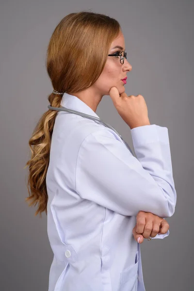 Молода красива жінка-лікар з світлим волоссям на сірому фоні — стокове фото