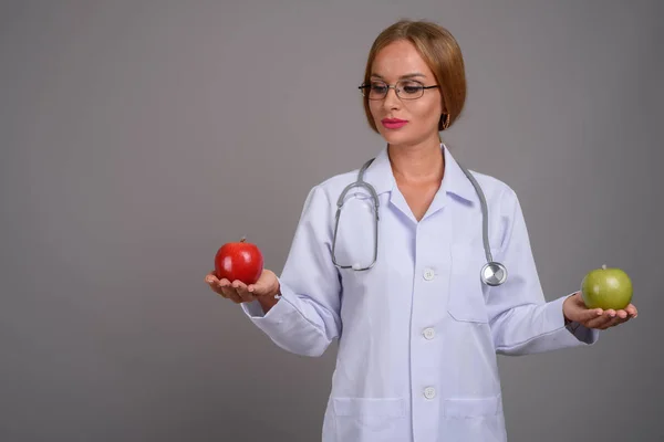 Jovem médico mulher bonita com cabelo loiro contra backgr cinza — Fotografia de Stock