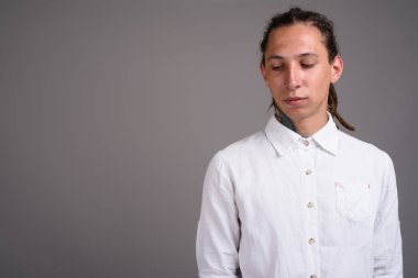 Studio shot of young businessman with dreadlocks against gray background