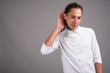 Studio shot of young businessman with dreadlocks against gray background