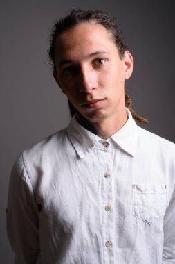 Studio shot of young businessman with dreadlocks against gray background