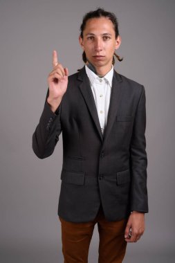 Studio shot of young businessman with dreadlocks against gray background