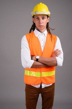 Studio shot of young man construction worker against gray background