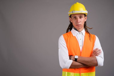 Studio shot of young man construction worker against gray background