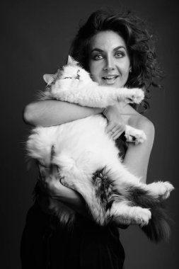 Studio shot of young beautiful woman with curly hair posing against gray background in black and white