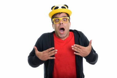 Studio shot of young Persian man looking shocked while wearing cute hat and yellow eyeglasses isolated against white background