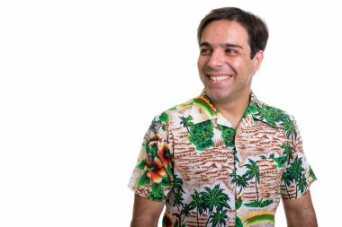 Studio shot of young happy Persian tourist man smiling and thinking while wearing Hawaiian shirt isolated against white background