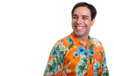 Studio shot of young happy Persian tourist man smiling and thinking while wearing Hawaiian shirt isolated against white background