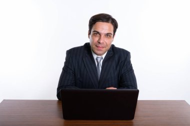 Genç İranlı iş adamının beyaz arka planda dizüstü bilgisayarla oturduğu bir stüdyo fotoğrafı.