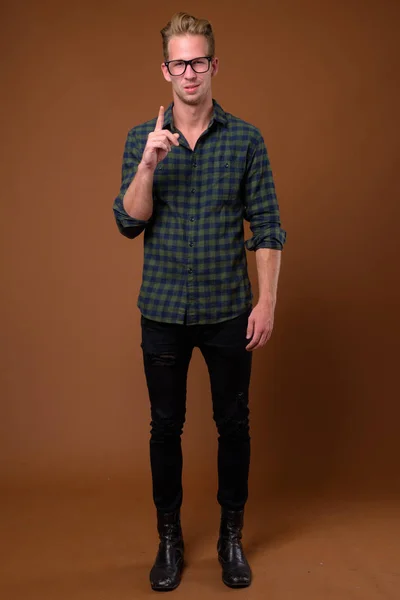工作室拍摄的年轻英俊男子穿着绿色格子衬衫反对棕色背景 — 图库照片