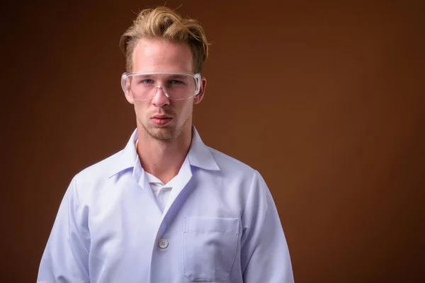 Studioaufnahme Eines Jungen Gutaussehenden Mannes Mit Schutzbrille Vor Braunem Hintergrund — Stockfoto