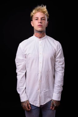 Studio shot of young handsome rebellious businessman with blond hair against black background