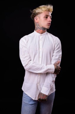 Studio shot of young handsome rebellious businessman with blond hair against black background