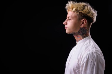 Studio shot of young handsome rebellious businessman with blond hair against black background