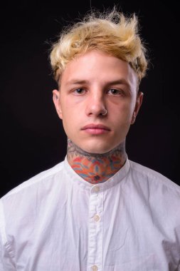 Studio shot of young handsome rebellious businessman with blond hair against black background