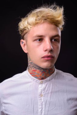 Studio shot of young handsome rebellious businessman with blond hair against black background