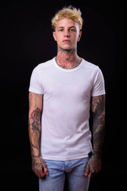 Studio shot of young handsome rebellious man with blond hair against black background