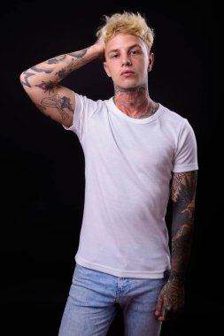 Studio shot of young handsome rebellious man with blond hair against black background