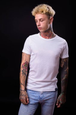 Studio shot of young handsome rebellious man with blond hair against black background