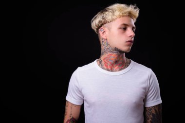 Studio shot of young handsome rebellious man with blond hair against black background